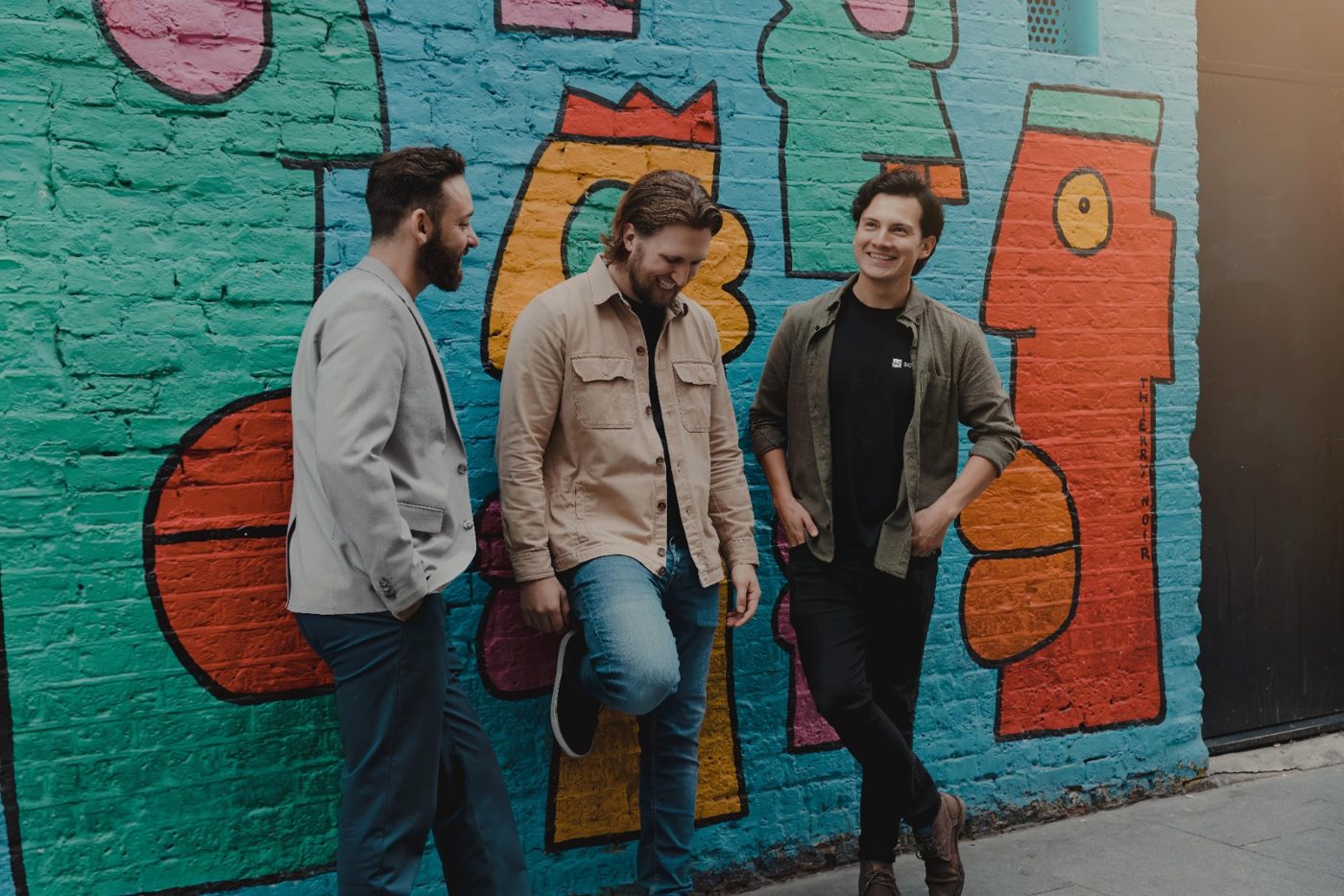 Yoann and two founders in front of a painted mural